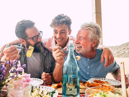 Bedstefar, far og søn spiser middag sammen og griner